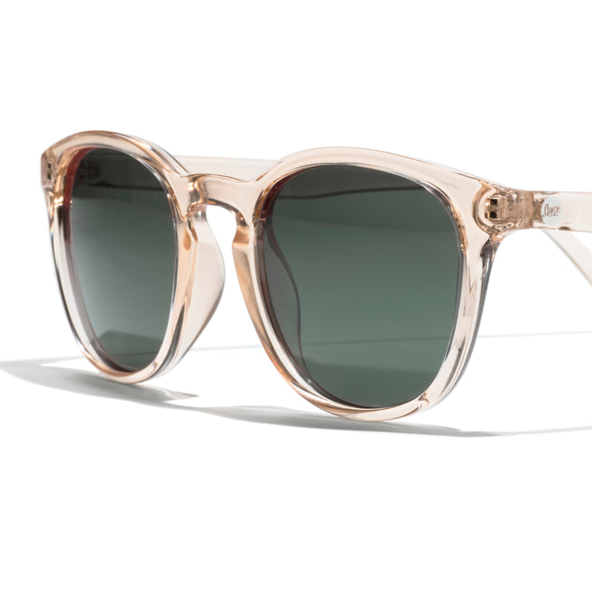 Sunglasses with a beige frame and dark lenses on a white background