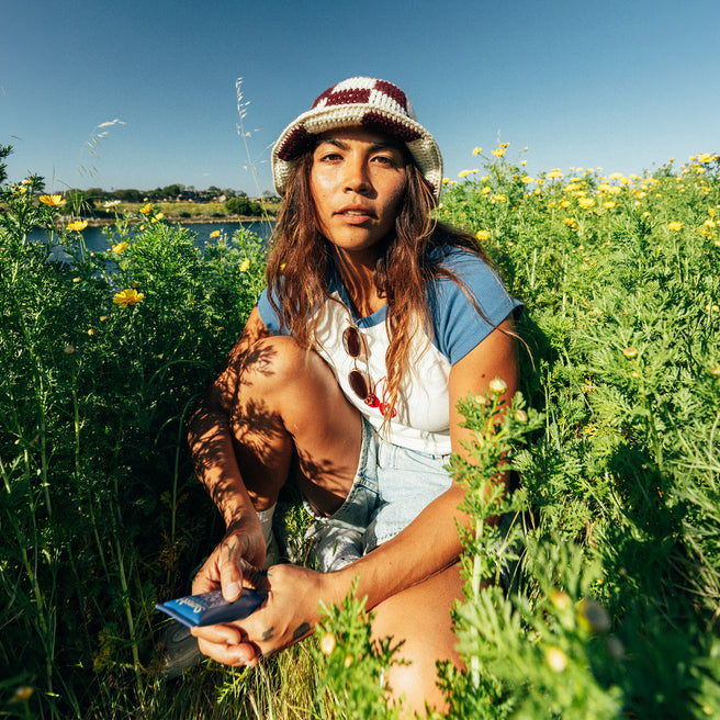Sol Power SPF 50 Sunscreen - 1.7 Fl oz / 50 mL - Woman in a field of flowers holding a phone
