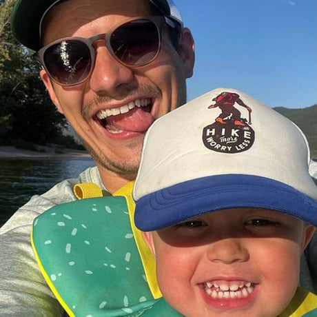 Man and child smiling outdoors with a scenic background