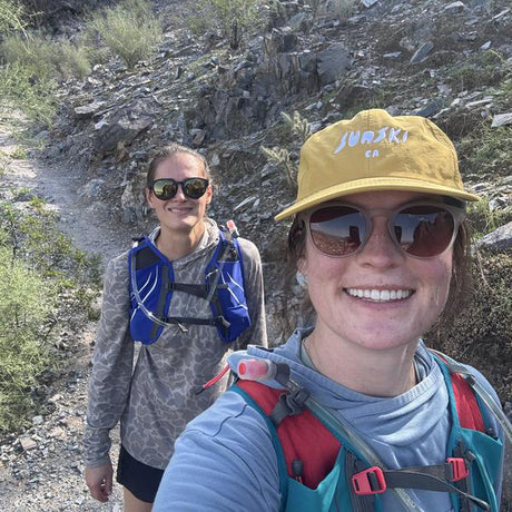 Woman wearing yellow hat and sunglasses hiking with a friend in the mountains