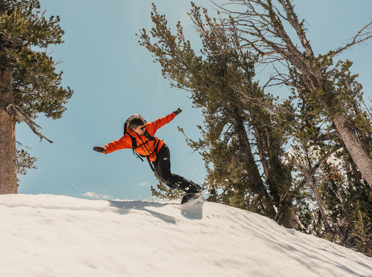 Person snowboarding in a snowy landscape with trees