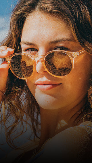 Close-up of a person wearing round sunglasses with a blurred background