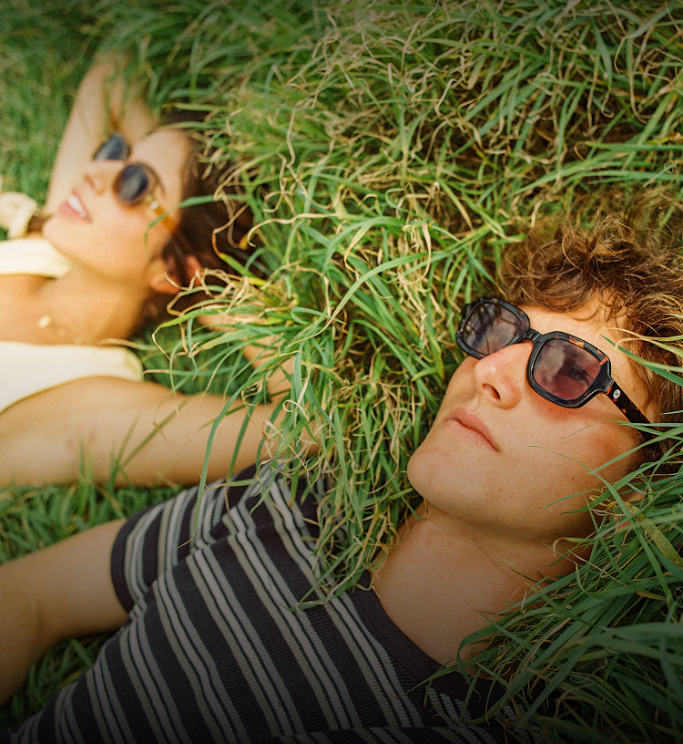 Two people lying on grass wearing sunglasses