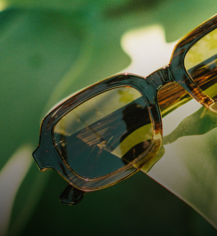 Sunglasses with reflective lenses on a blurred natural background