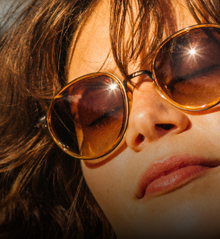 Close-up of a person wearing large sunglasses with a blurred background