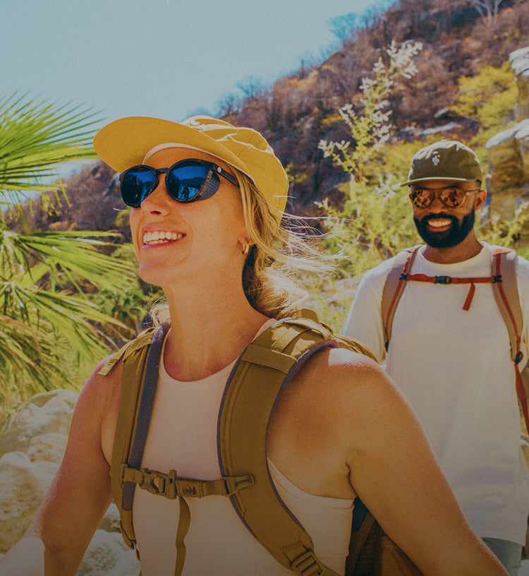 Two hikers in mirrored sunglasses smiling on a sunny desert trail