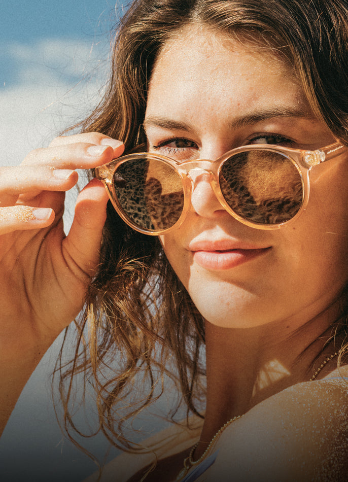 Close-up of a person wearing round sunglasses with a blurred background