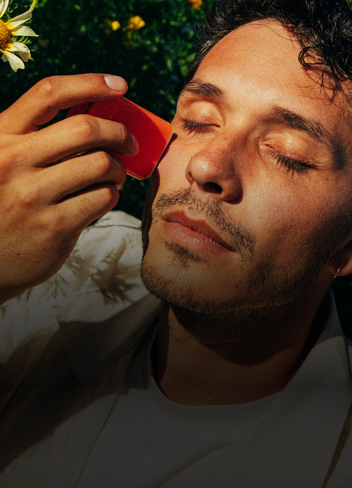 Person applying sunscreen to their face outdoors