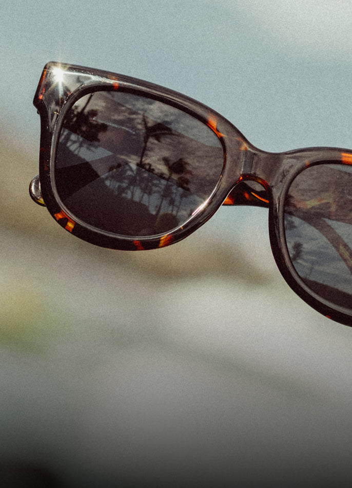 Sunglasses with tortoiseshell frame and reflective lenses on a blurred background