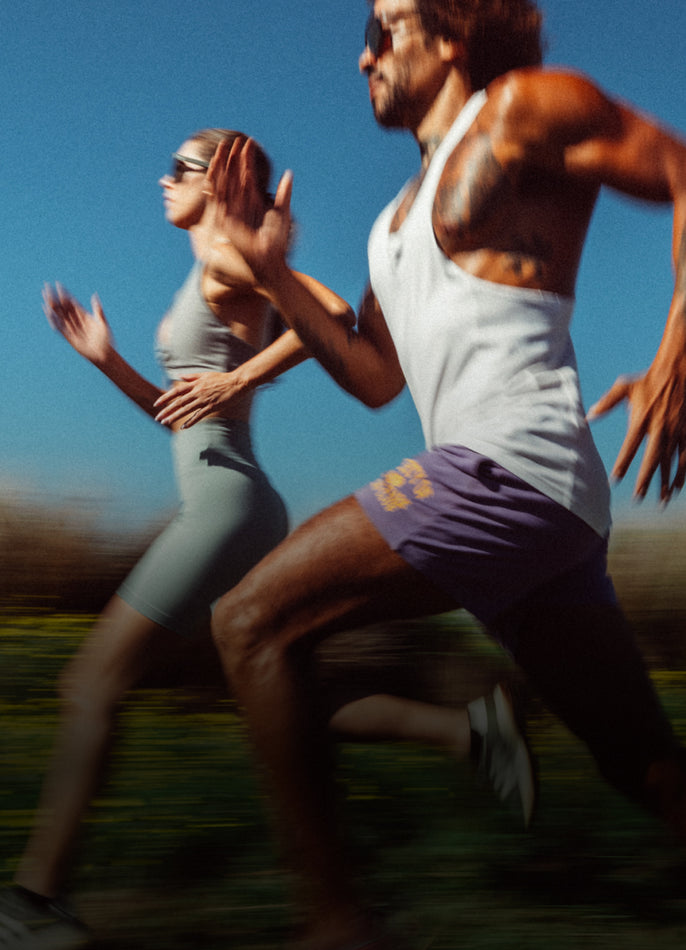 Two runners in athletic wear running outdoors on a clear day.