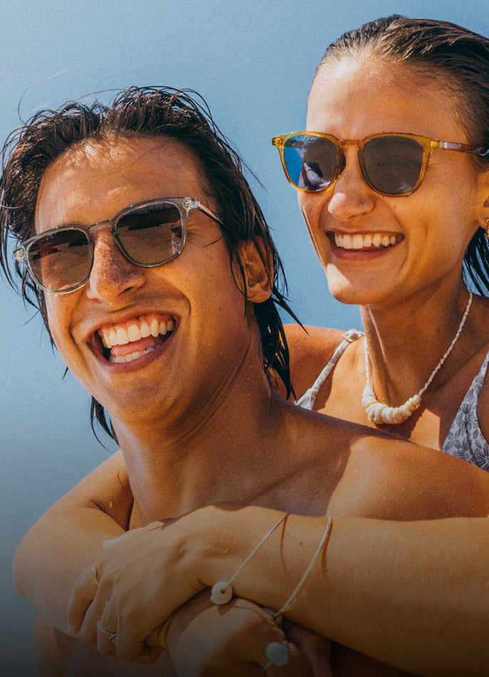 Two people wearing sunglasses with a clear blue sky background