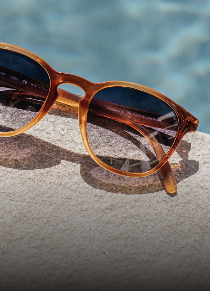 Brown sunglasses with reflective lenses on a textured surface with a blurred blue background